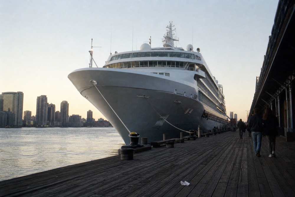 A cruise vessel moored at a Boston pier at early evening with the city skyline behind it