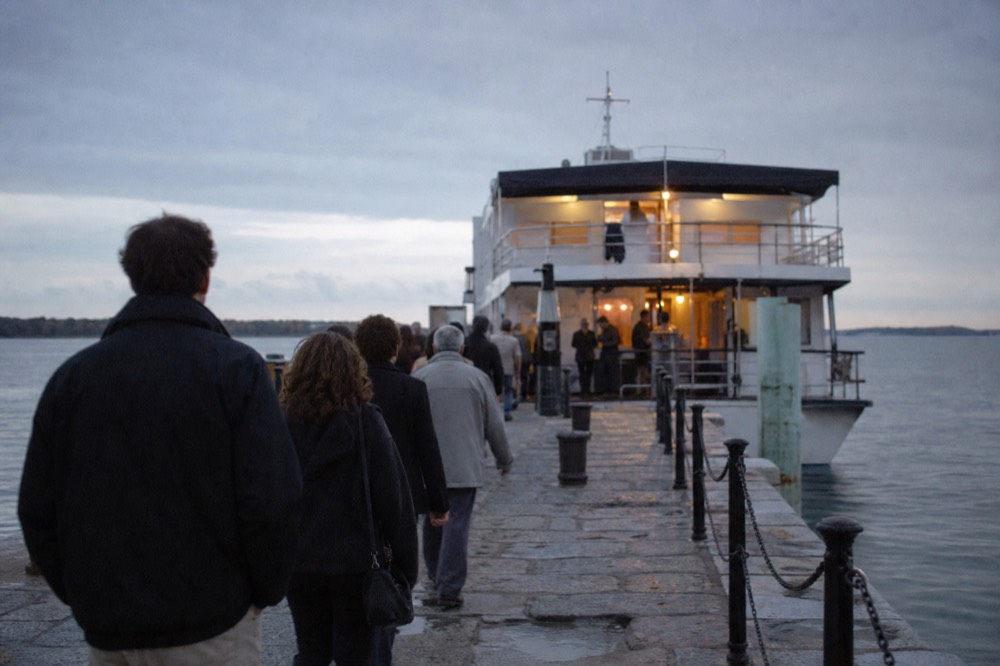 Passengers walking along a pier toward a docked dinner cruise vessel in Boston at dusk