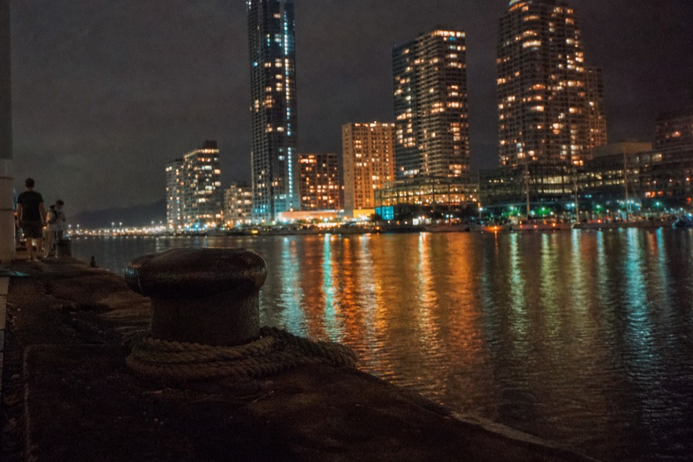 City lights reflecting on dark harbor water at night
