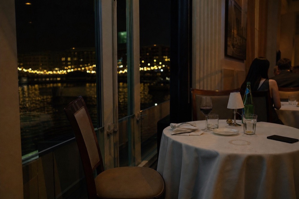 Table setting beside a window with harbor lights outside at night