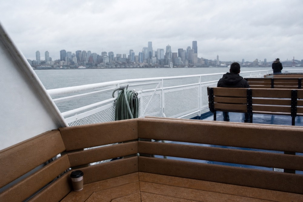 An open observation deck on a harbor cruise vessel with the Boston skyline across the water