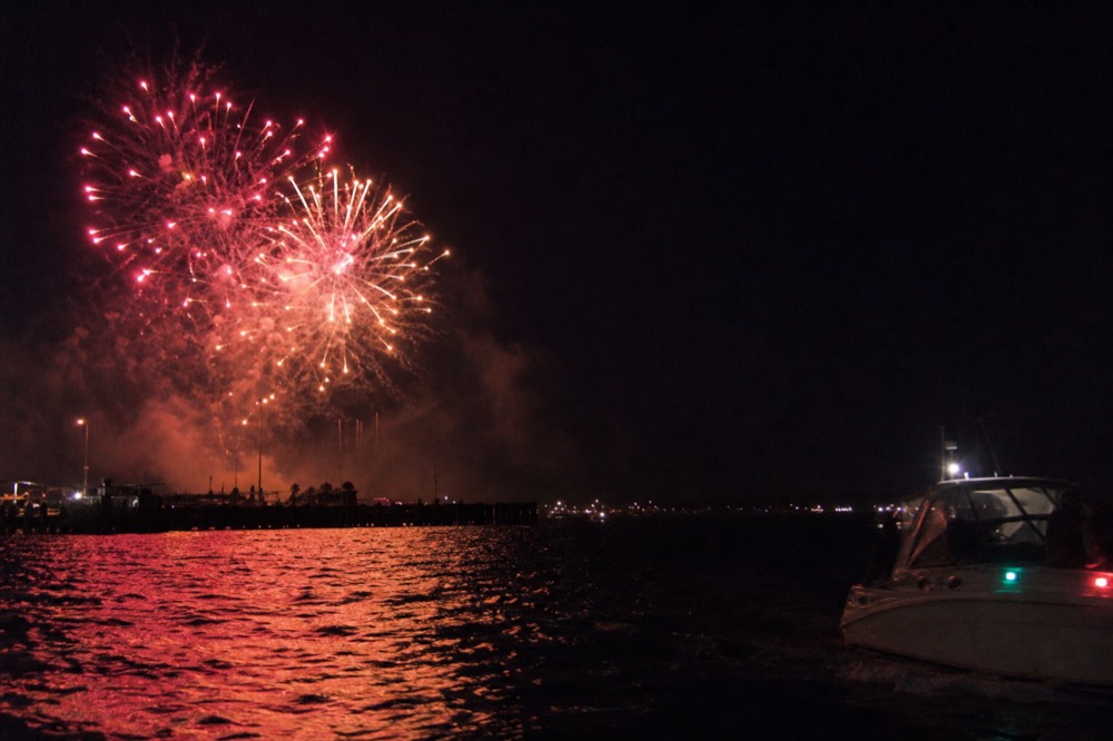 Fireworks bursting over Boston Harbor at night