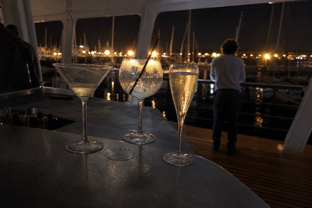 Cocktail glasses on a cruise bar counter with harbor lights in the background